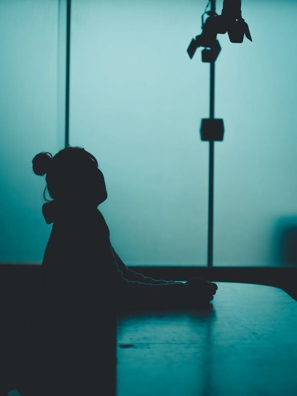 Woman in a calm yoga pose against a dark background with light blue accents.